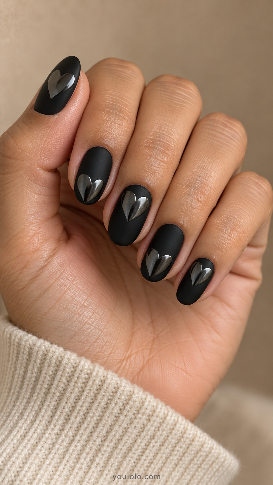 Medium oval matte-black nails each with one broad flat isolated dark gunmetal chrome heart, alternate heart placement upper or lower nail