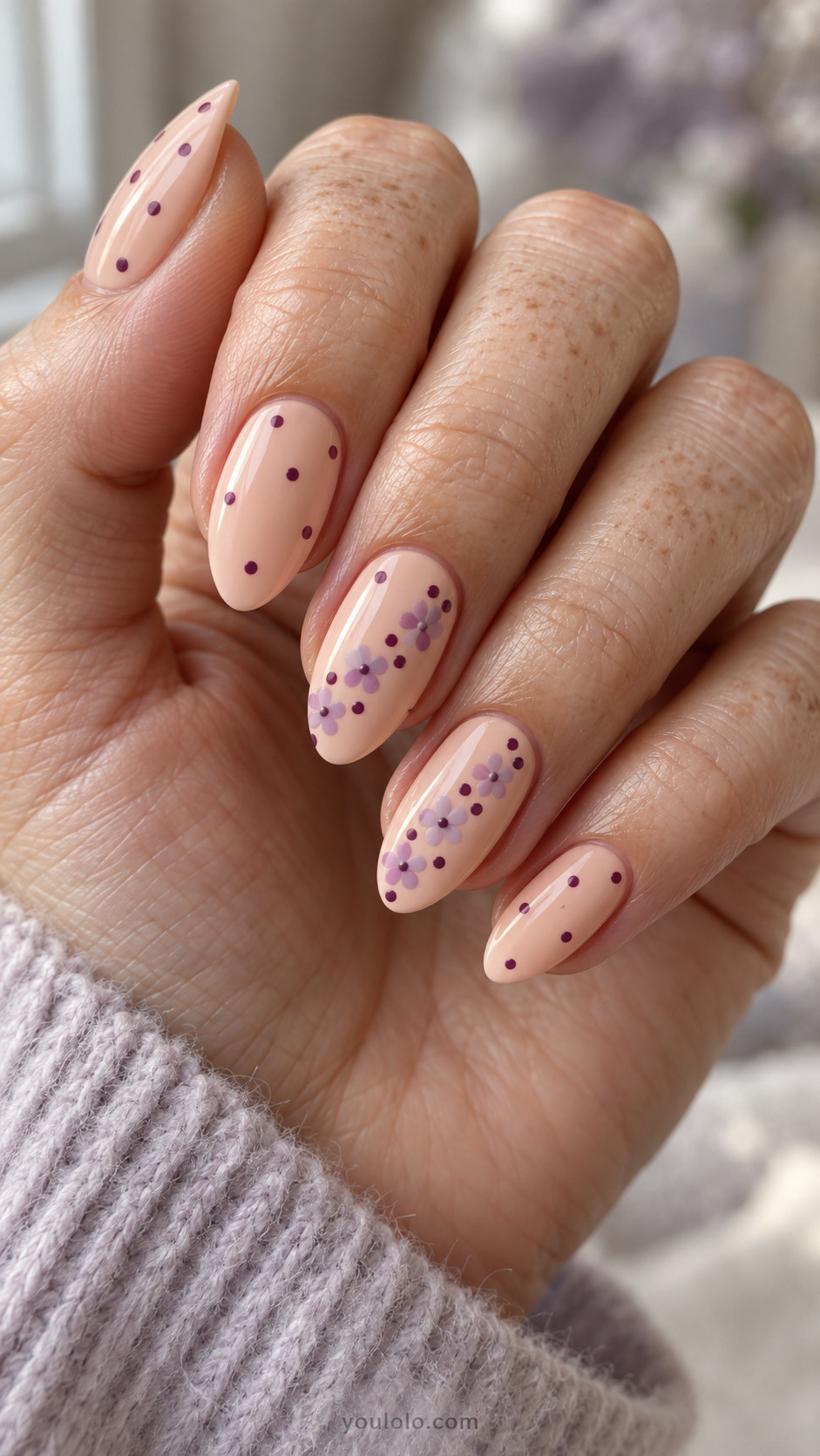 Peach almond nails with plum dots and lilac floral accents.