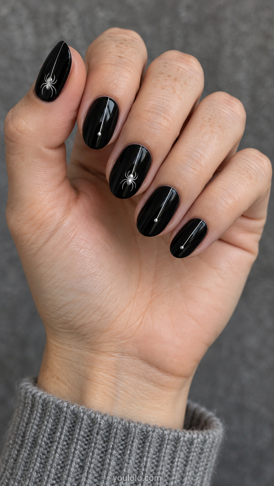 Medium oval glossy black nails with one small silver painted spider and extremely fine thread on two nails, other three single silver descending thread ending small dot