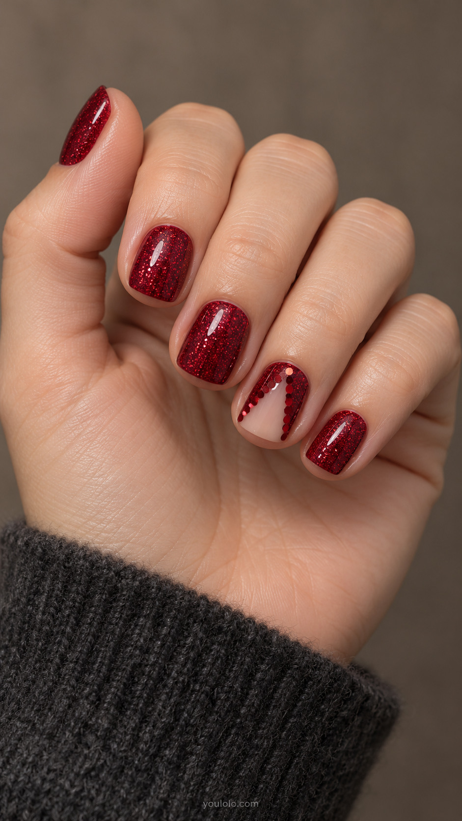 Ruby glitter nails with a nude triangular window on the ring finger