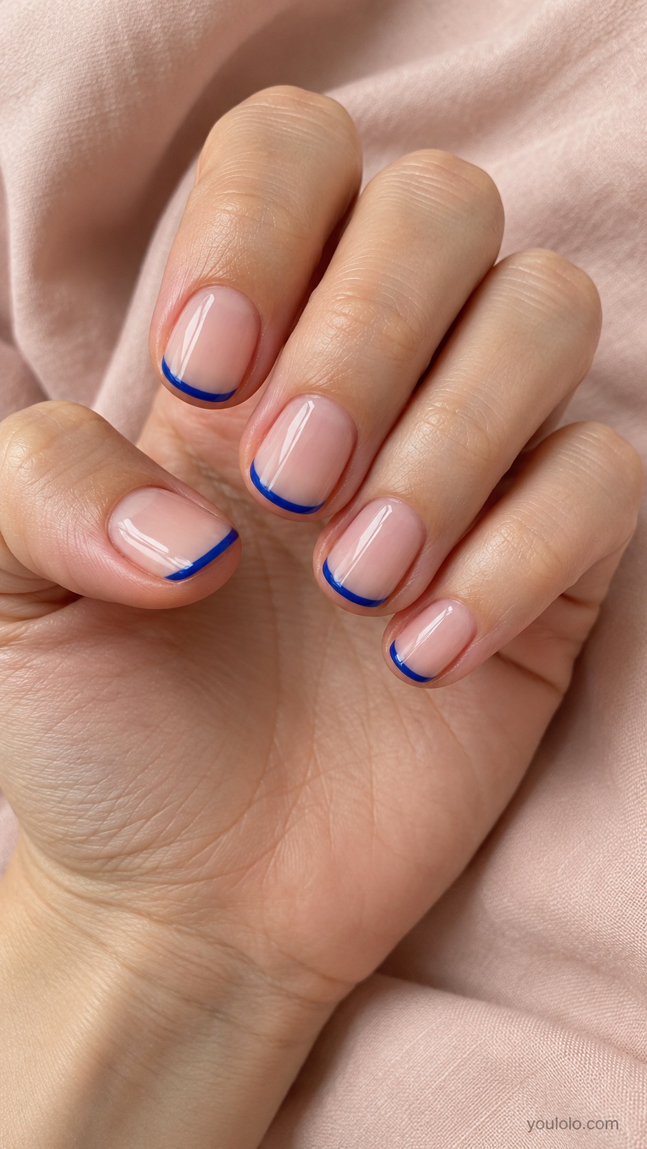 Short round nails clear neutral pink base with slim cobalt blue French tips