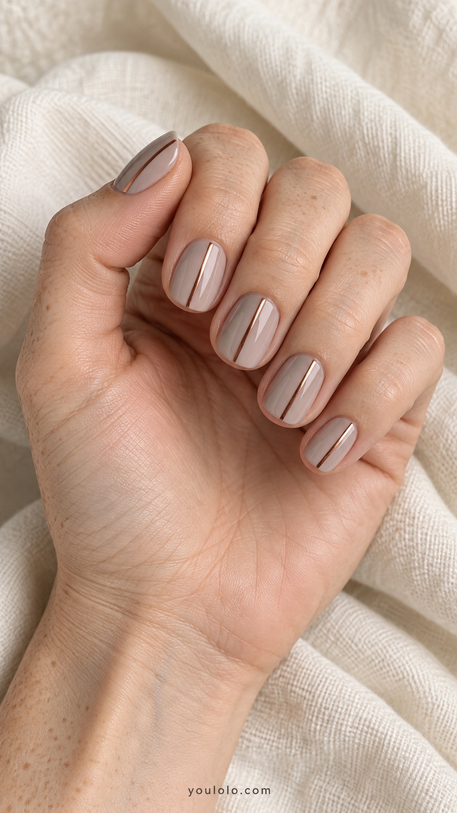 Short squoval nails pale taupe base one thin copper vertical line offset on each nail