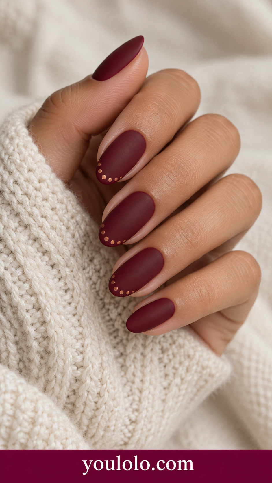 Wine Copper Dot Border: medium oval matte wine nails tiny evenly spaced copper painted dots along one tip edge on two nails on a naturally posed adult hand