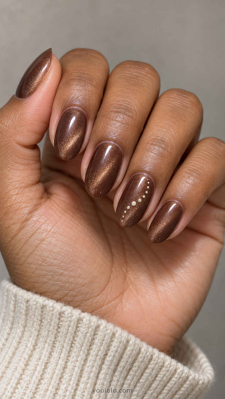 Medium oval nails: milk chocolate magnetic velvet nails with tiny flat cream dots forming a short curved trail on ring only, no stars.