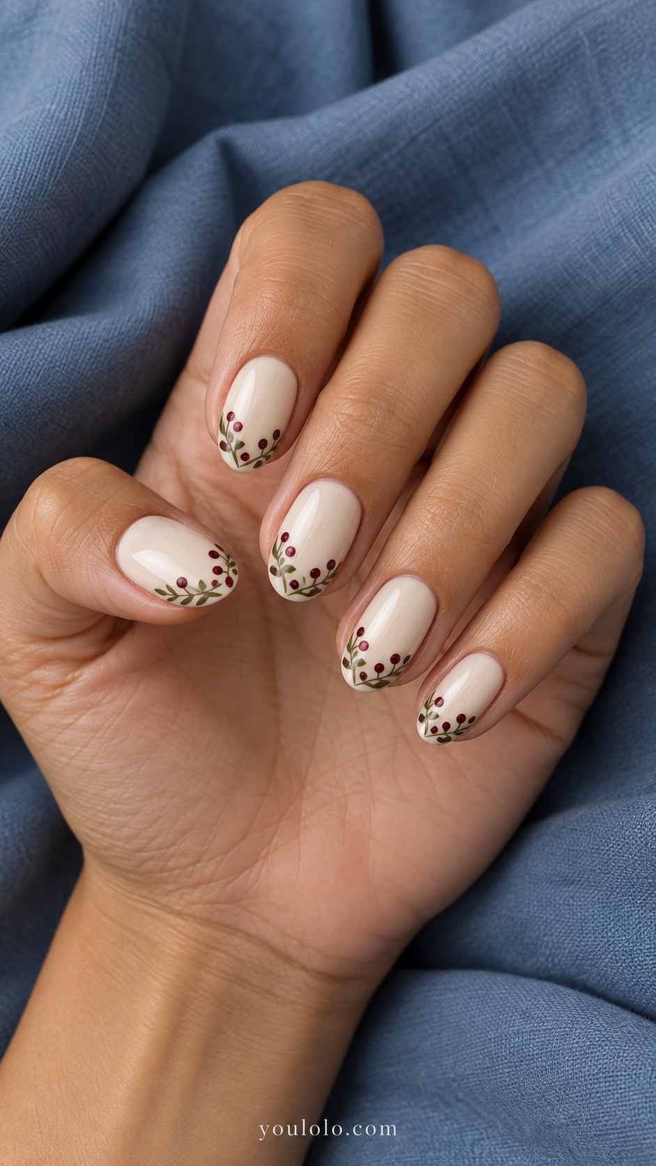 Medium oval nails ivory base tiny burgundy berry dots and muted olive leaf garland along tips