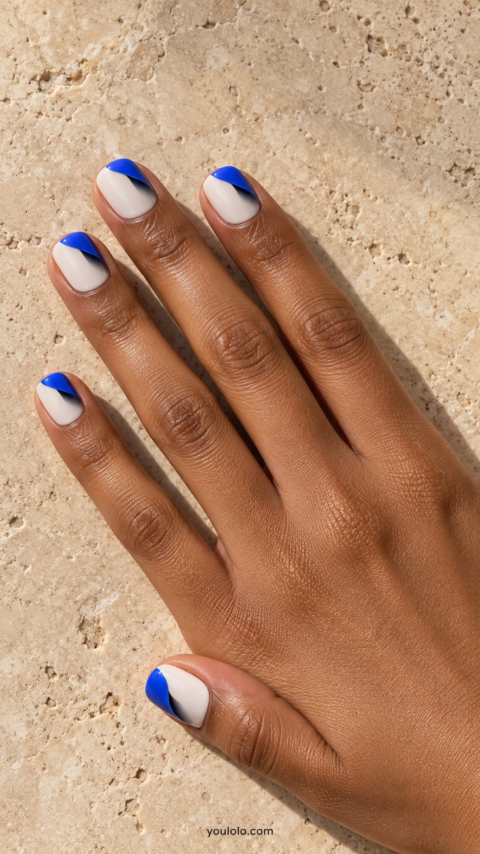 Paper-Curl Corners: short squoval cream nails, painted cobalt corner curl with dark shadow suggesting peeled paper, flat surface