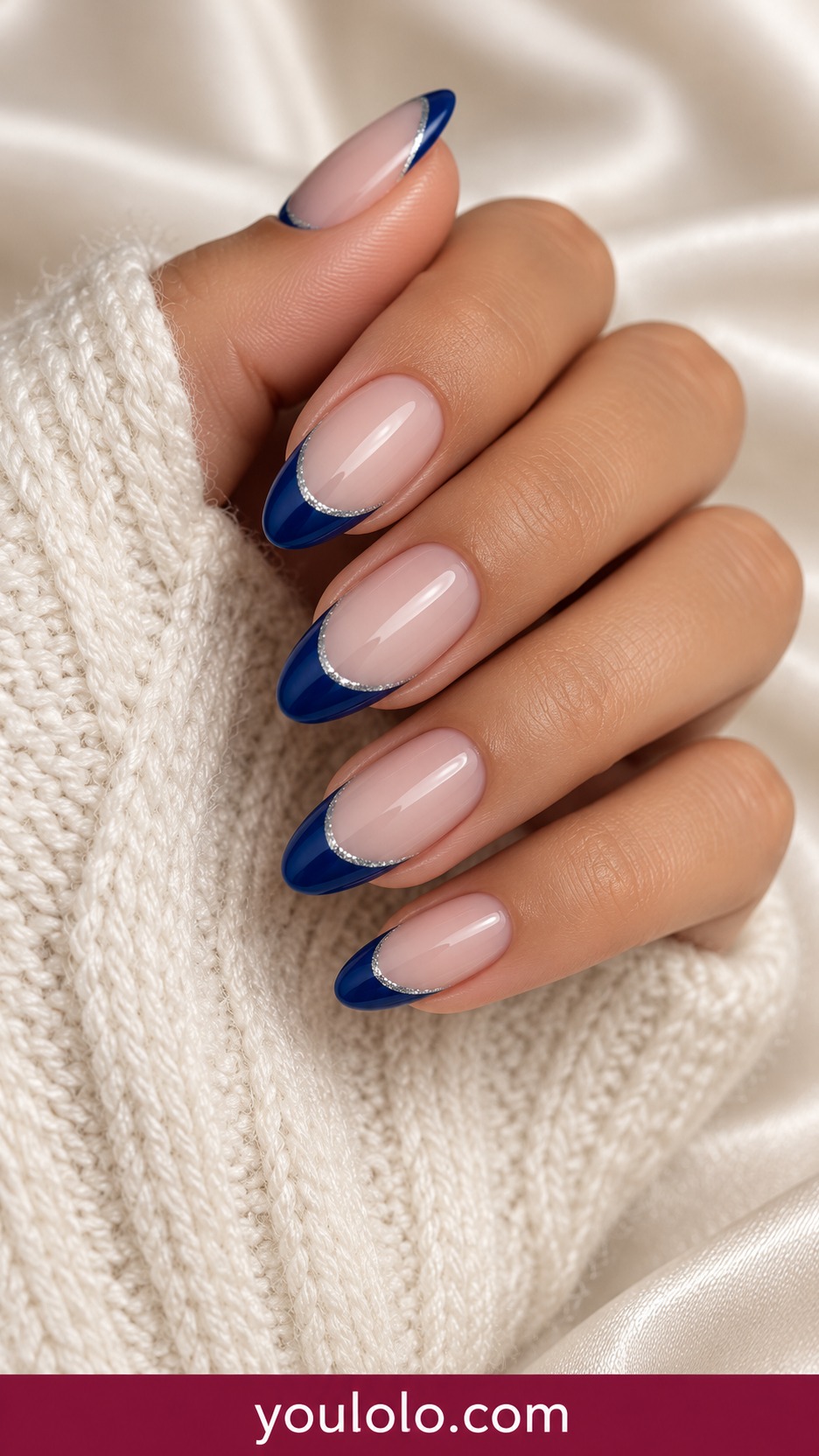 Medium almond sheer neutral base with deep sapphire blue French tips and fine silver outline on a naturally curled young adult hand