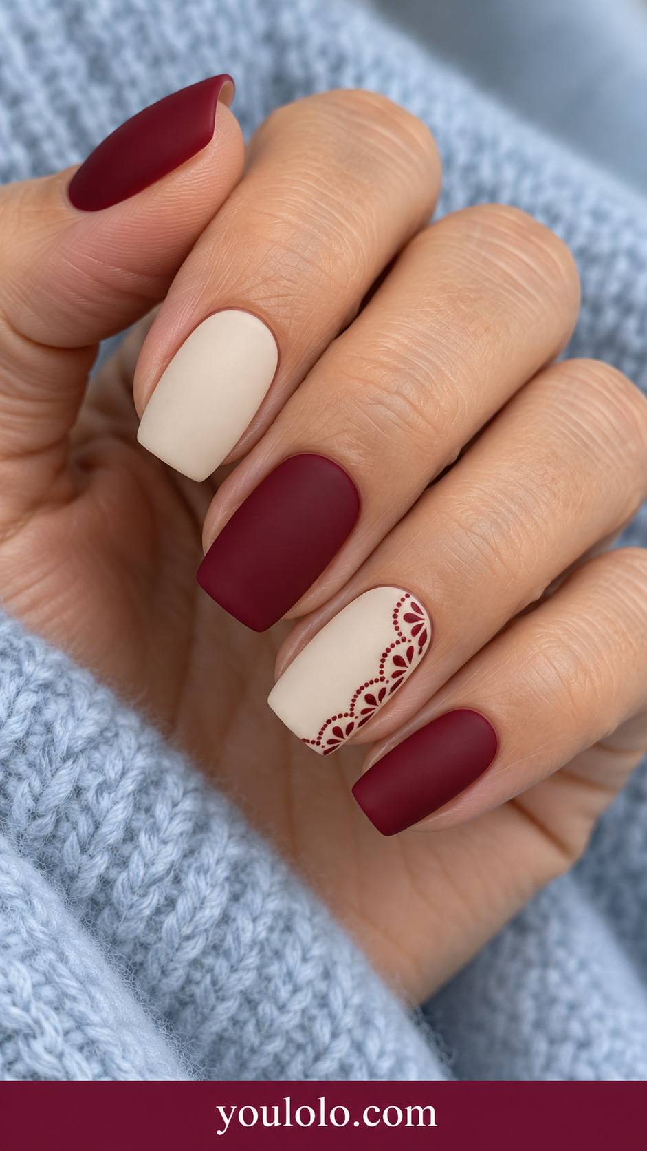 medium square alternating deep red and warm ivory nails, ivory ring nail with fine red scalloped curved border and tiny red dots on a naturally relaxed adult hand