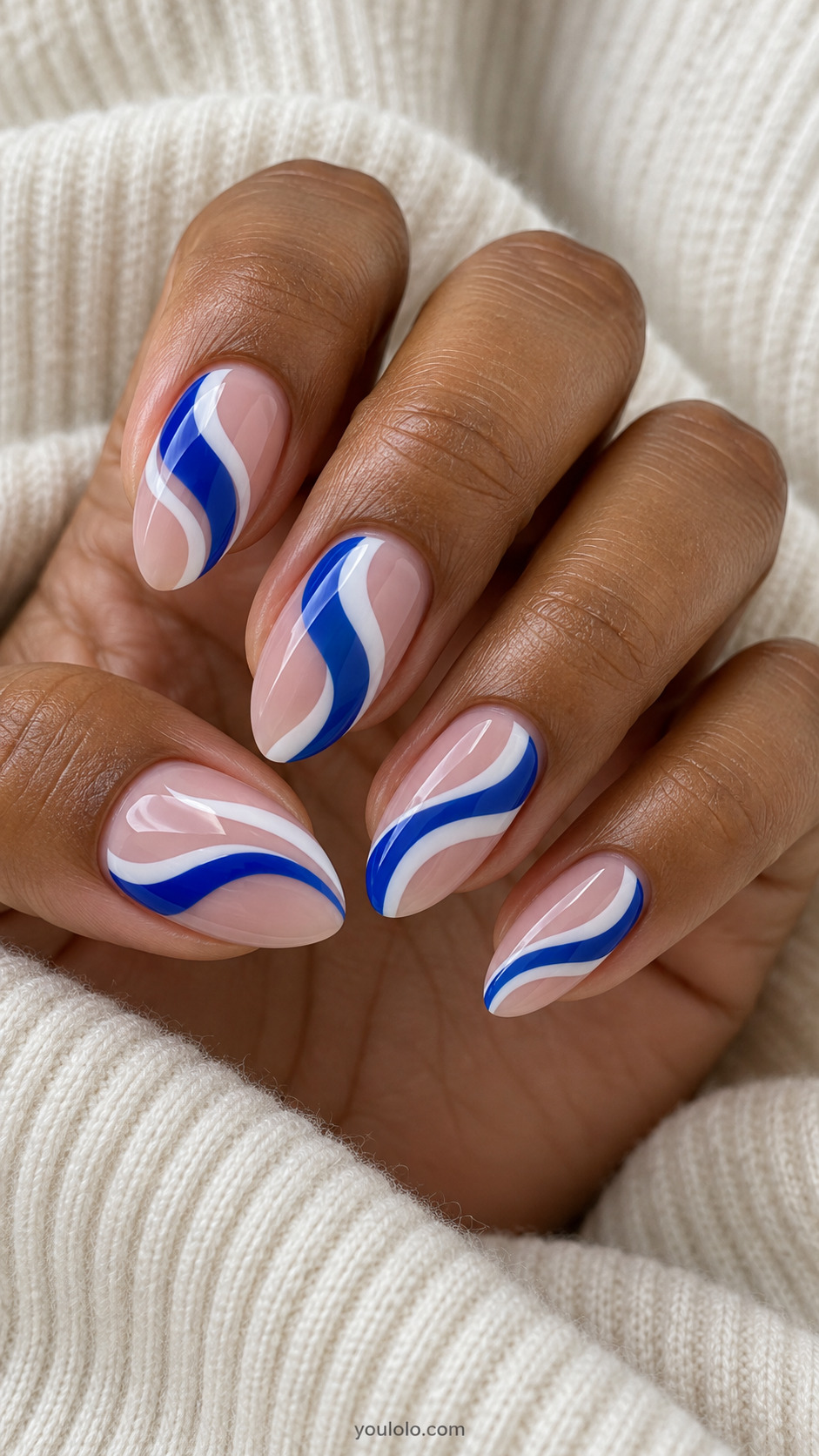 Nude almond nails with flowing royal blue and white swirls