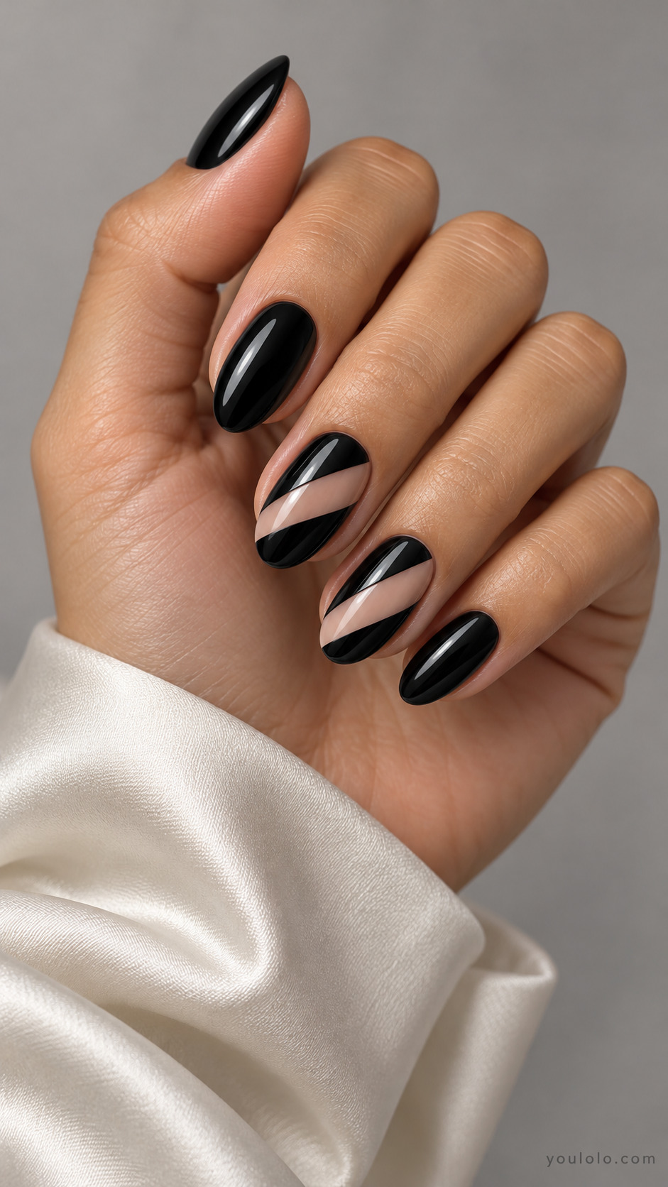 Black oval nails with diagonal nude bands on two accents