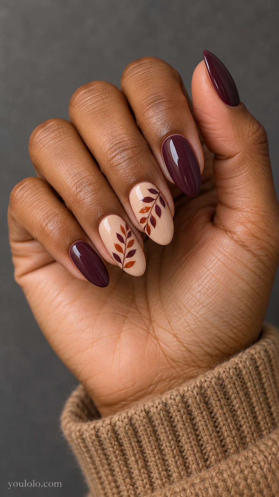 Medium almond nails with cream nude nails; diagonal rowan compound leaf trail in alternating burnt orange and deep plum leaflets runs across middle and ring nails; other fingers solid plum.