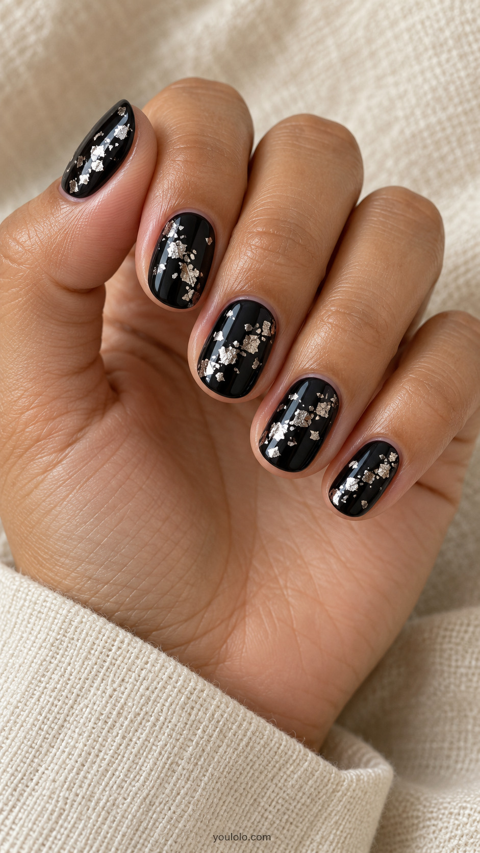 Short oval black nails scattered tiny irregular metallic silver torn-foil pieces distributed in narrow diagonal cloudy clusters, no stars lines or big single slash