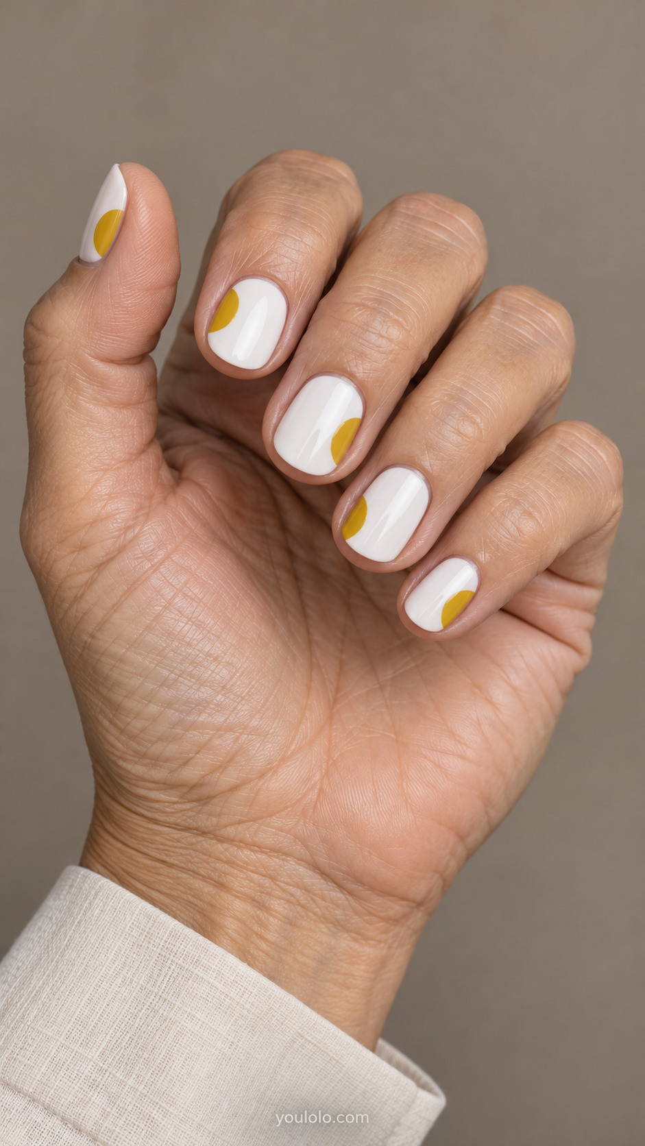 Short white round nails with mustard semicircles along the sides