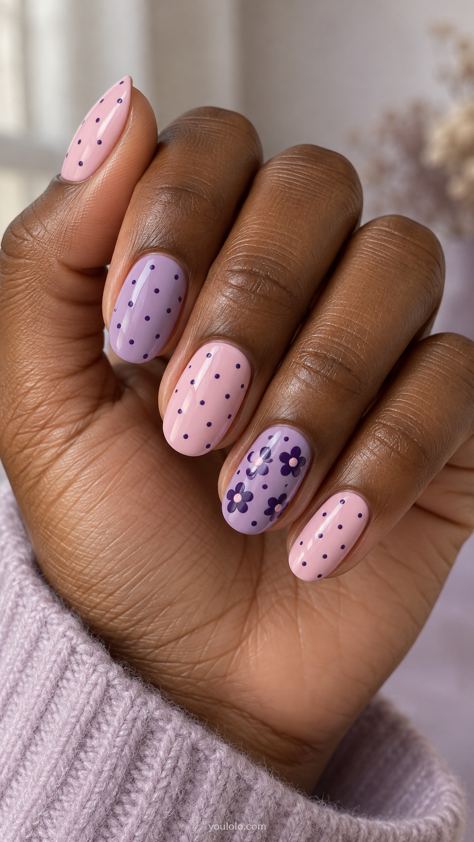 Pink and lilac oval nails with violet dots and a floral accent.