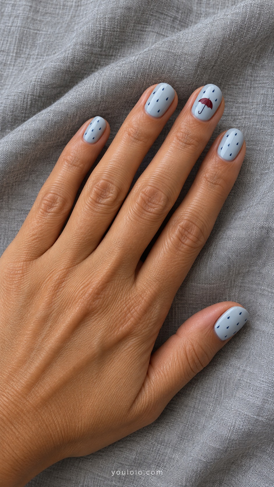 Short oval nails pale blue gray four nails ring with tiny burgundy umbrella other nails sparse tiny navy raindrops