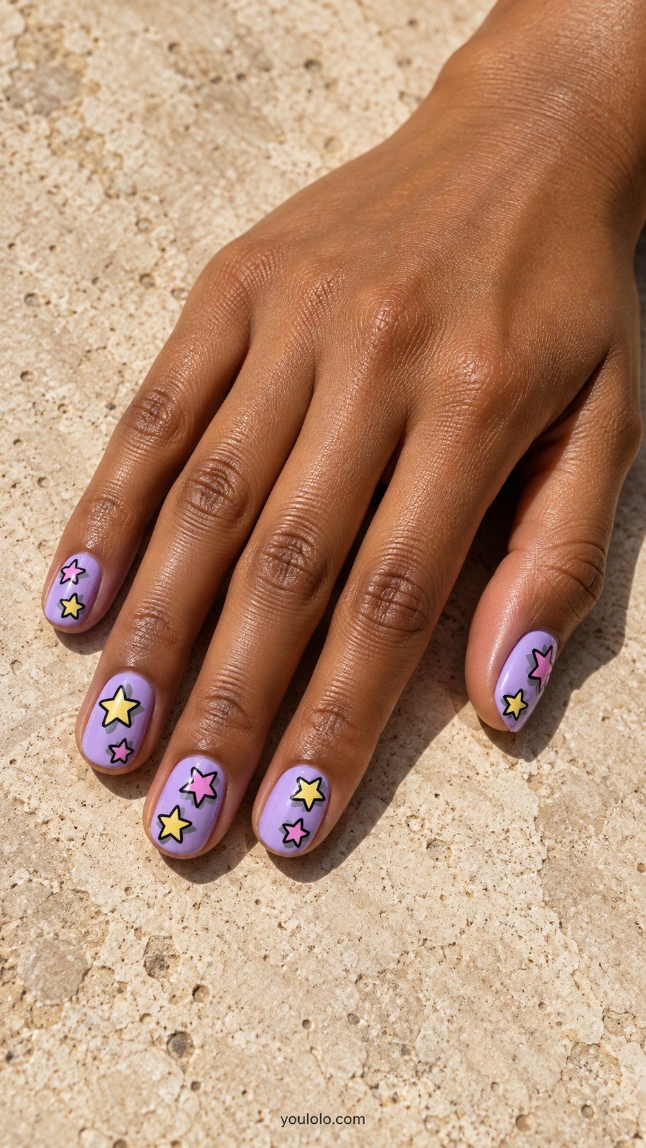Painted Sticker Stars: short rounded lavender nails, yellow and pink black-outlined flat star motifs with small gray painted shadows