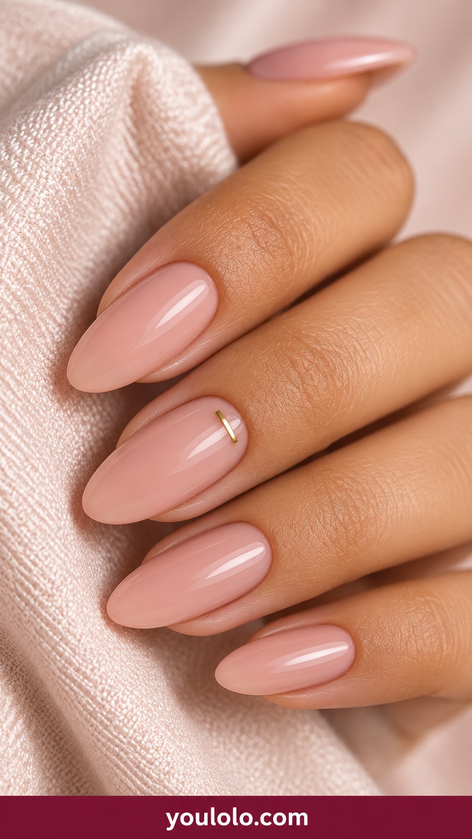 Medium oval pale nude pink nails single tiny horizontal gold dash near cuticle on one accent only on a naturally curled young adult hand