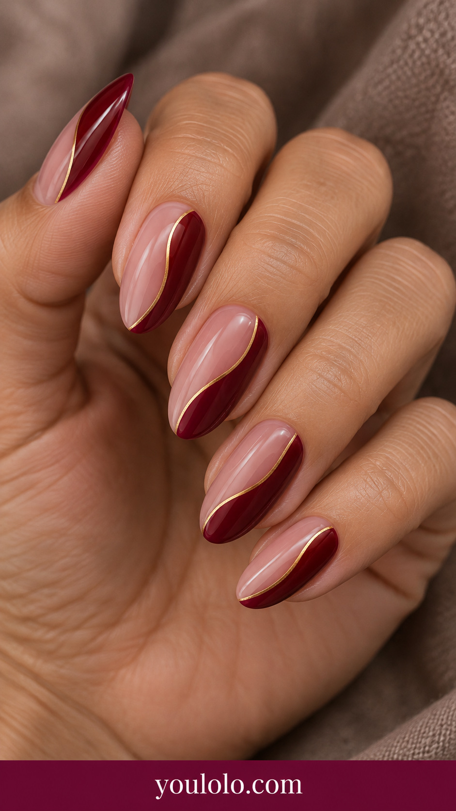 medium oval translucent pink nails with glossy ruby red asymmetrical side panels and very fine gold separator on a naturally relaxed adult hand