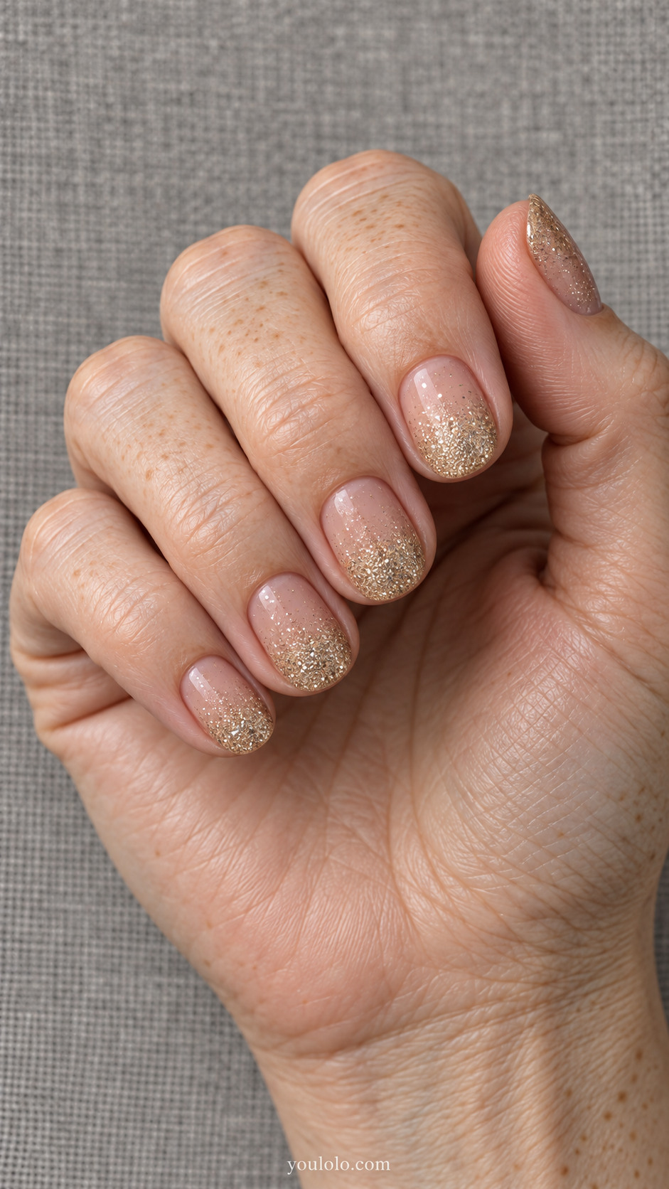 Short nude nails with champagne glitter gradually increasing toward the tips