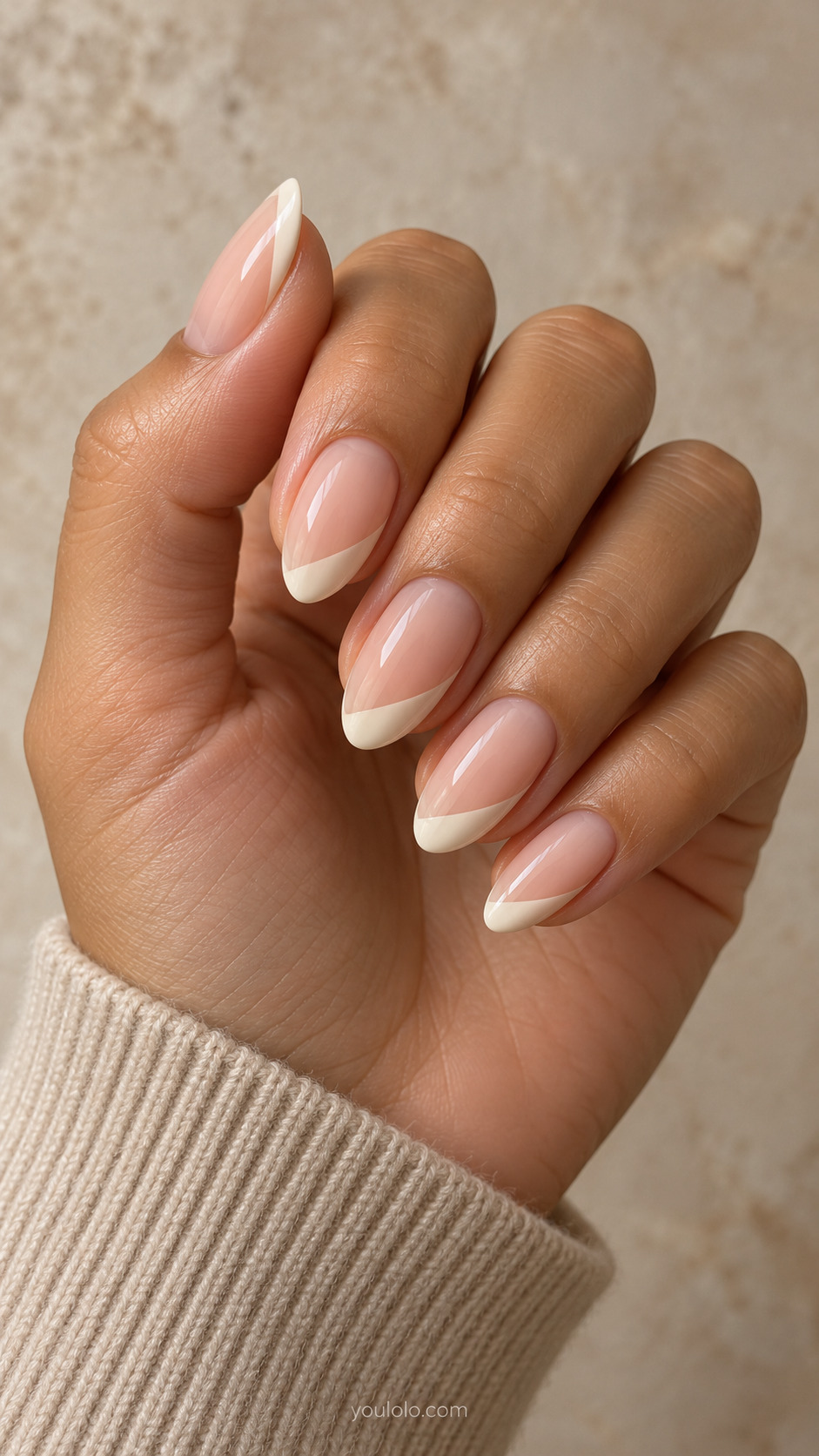 Medium almond nails with sheer peach bases and diagonal ivory tips sweeping across one corner.