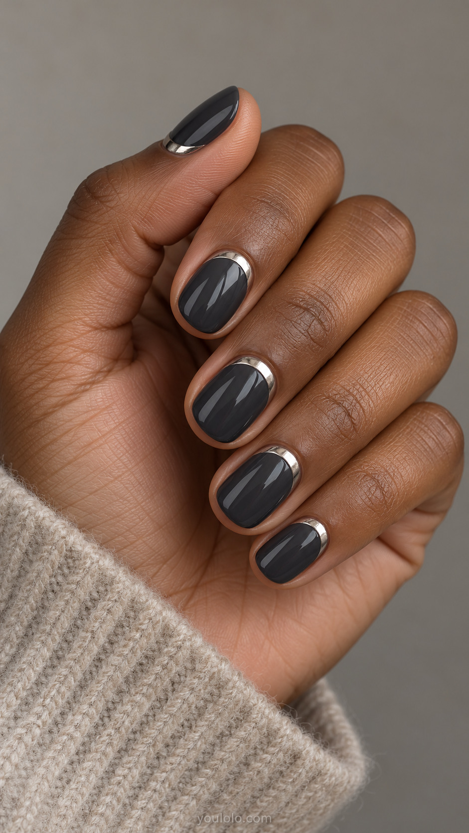 Glossy charcoal rounded nails with slim pewter-silver chrome cuffs near the cuticles.