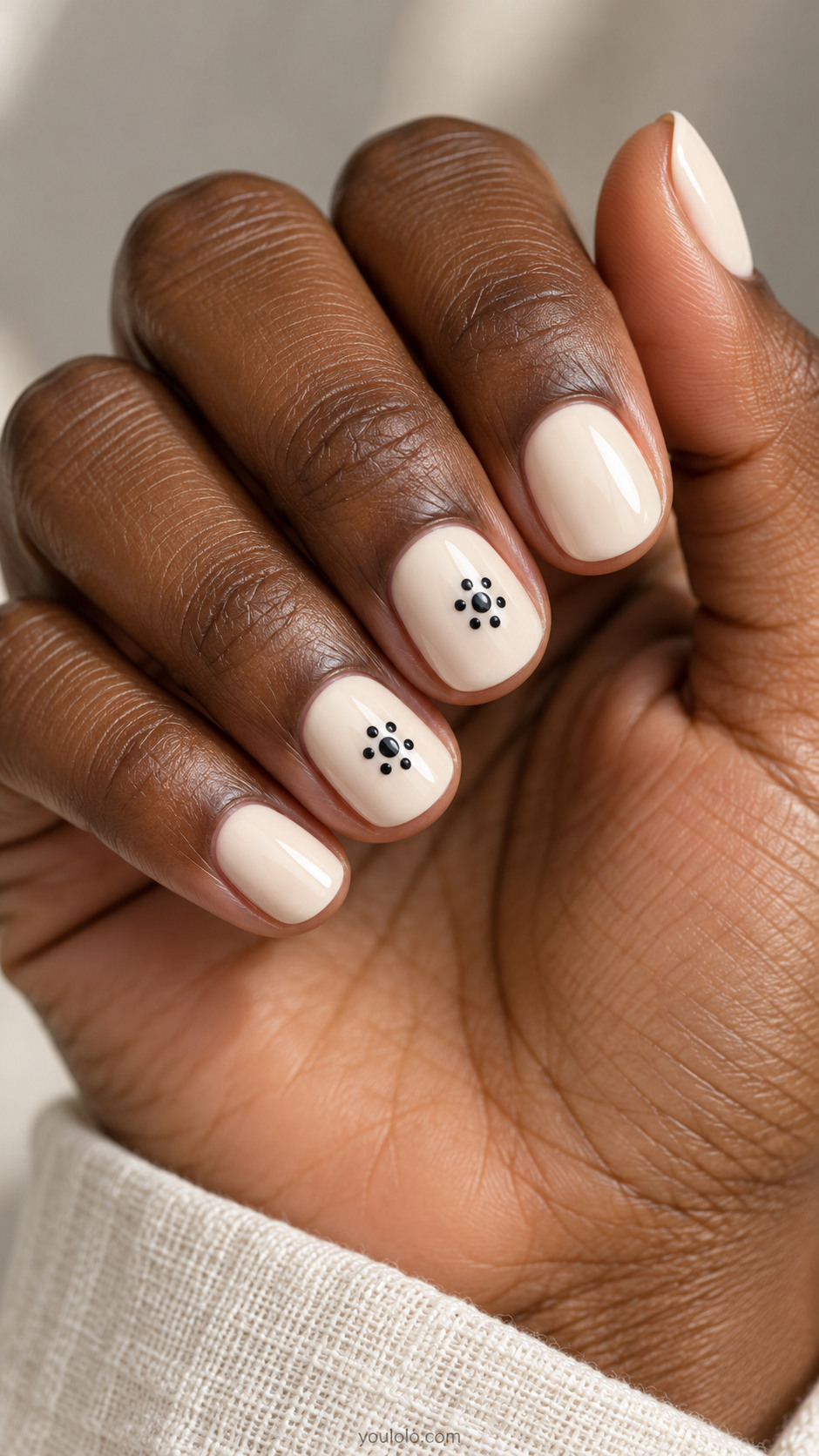 Short ivory nails with small black dot rosettes on two neighboring accent nails