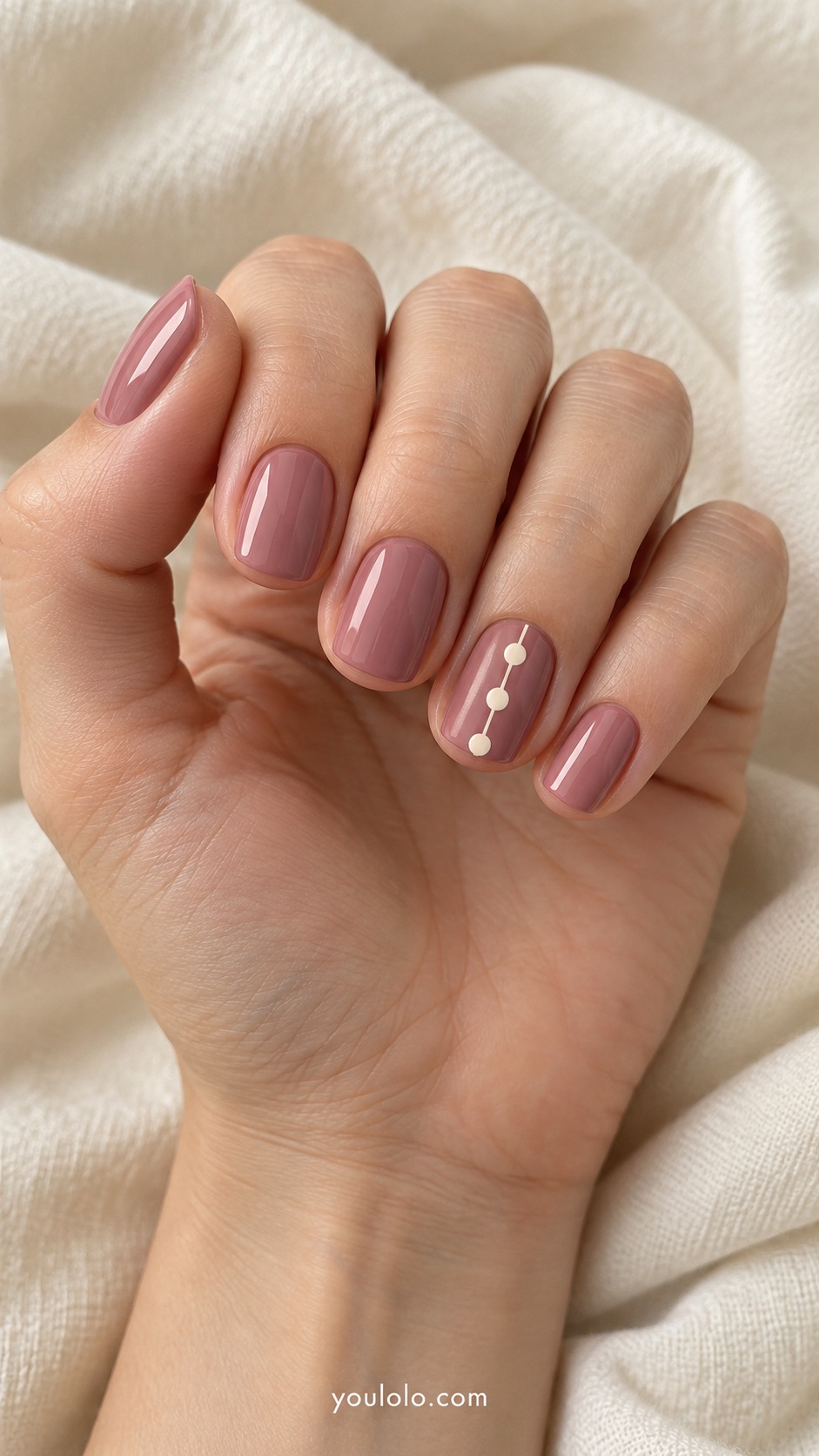 Short rounded square nails dusty rose base ring nail flat cream button dots connected by a thin cream vertical line