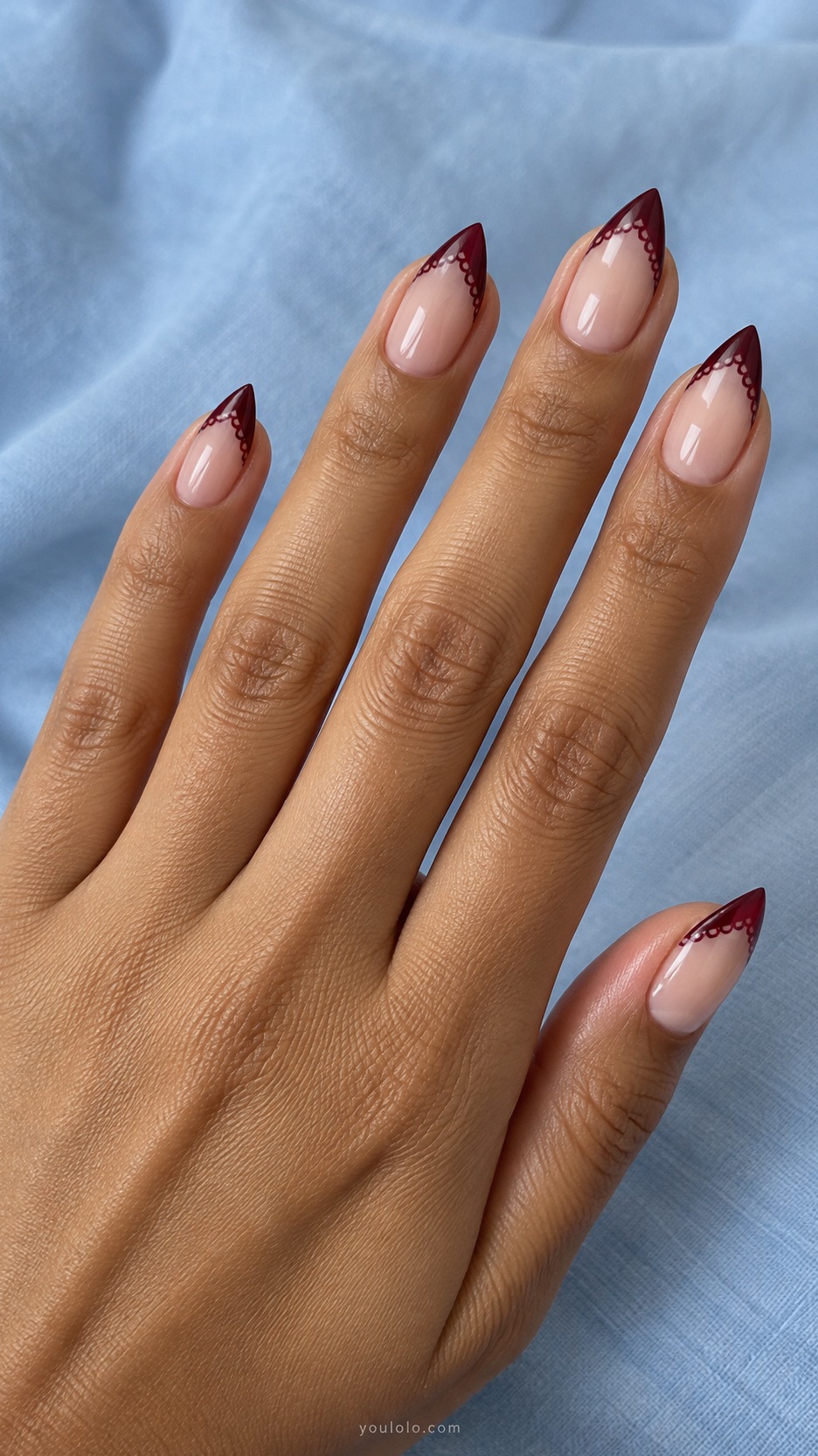 Short Stiletto French Nails: Burgundy Lace Edge manicure on a naturally posed hand