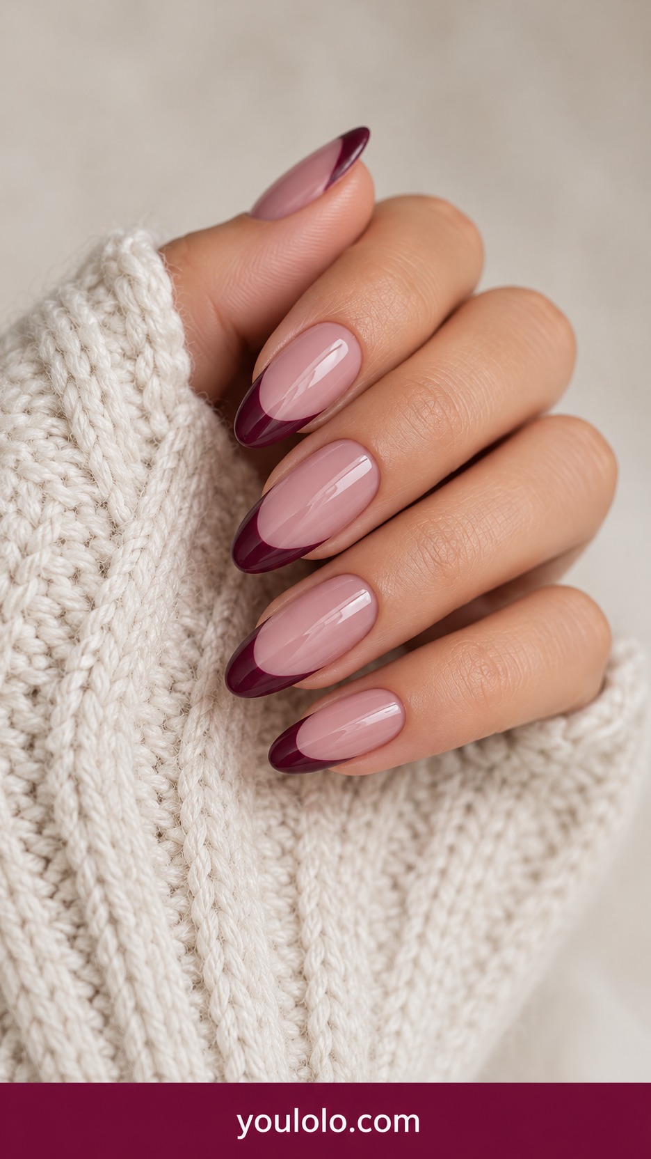Medium almond nude mauve base with deep plum curved French tips glossy on a naturally curled young adult hand