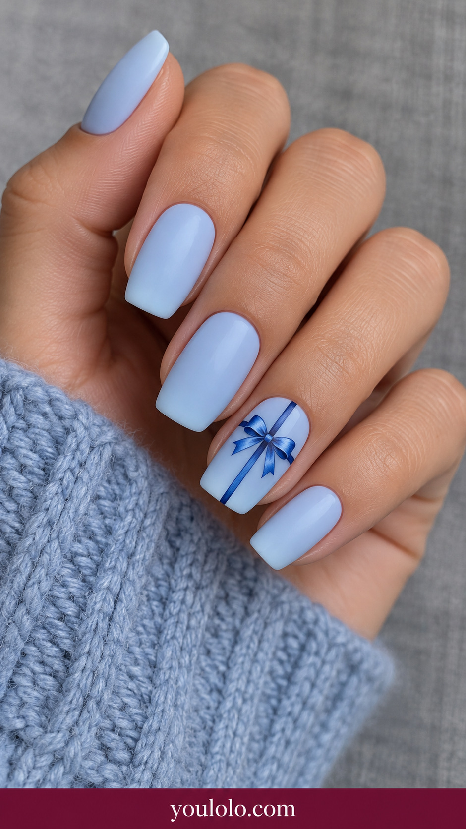 medium soft square pale blue nails ring nail fine cobalt cross ribbon with small painted blue bow, other nails plain on a naturally relaxed adult hand