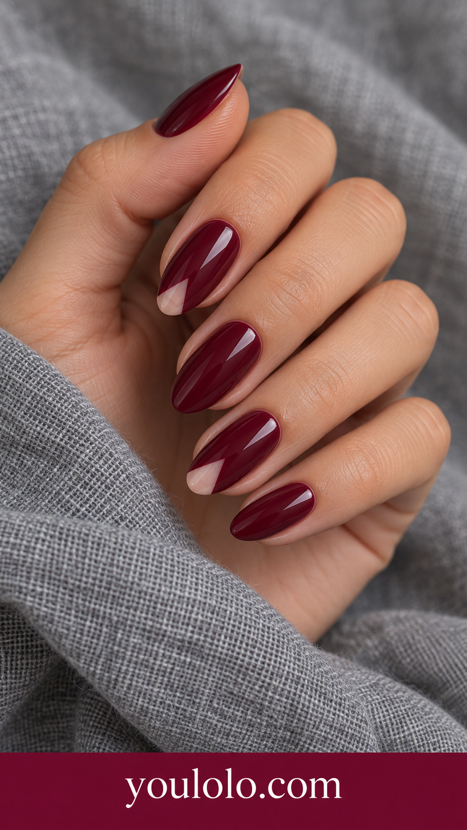 Maroon Cutout Triangle: medium oval maroon nails small sheer nude triangular cutout near tip on ring and index on a naturally posed adult hand