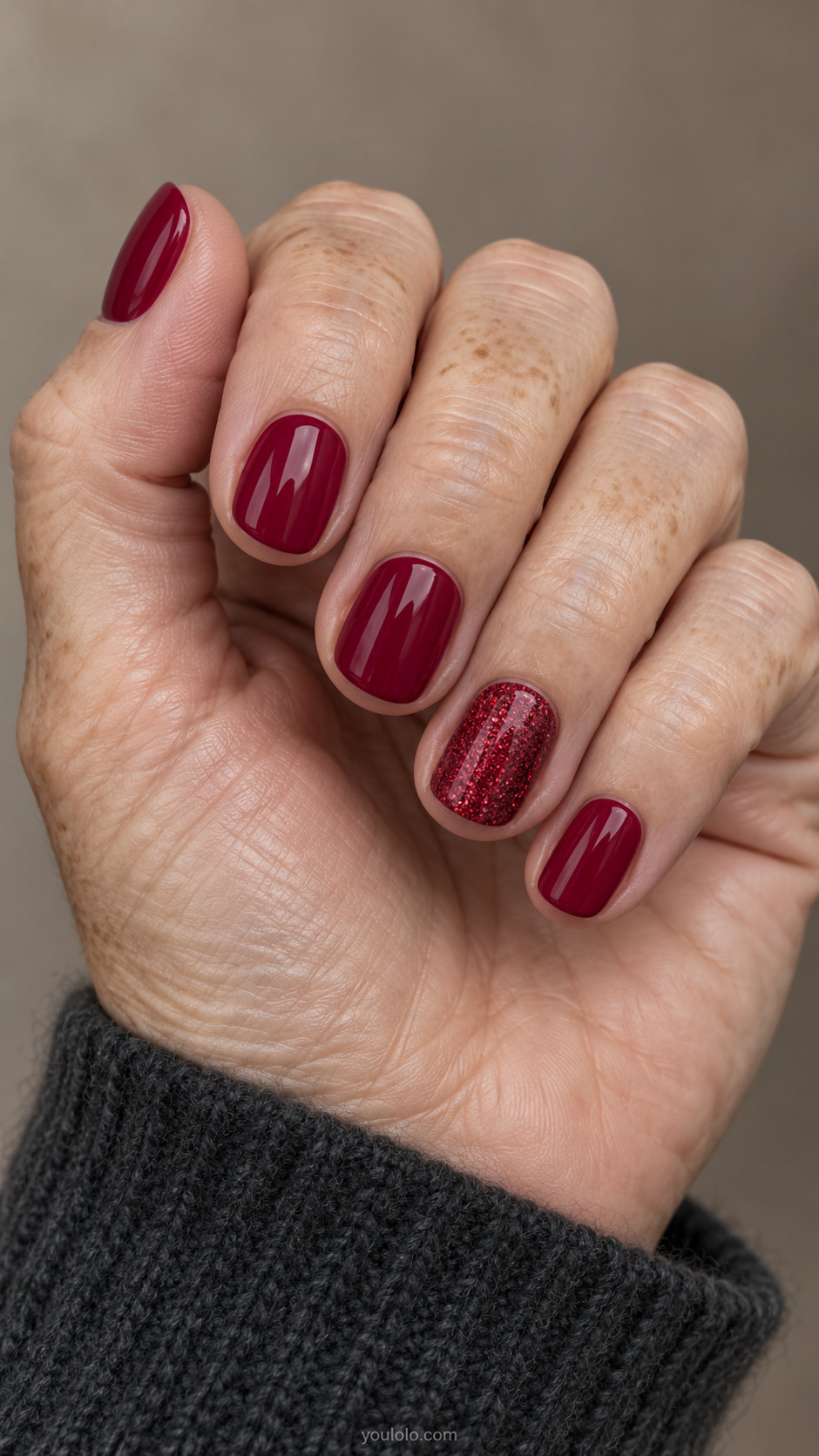 Short cranberry nails with one full ruby glitter ring accent