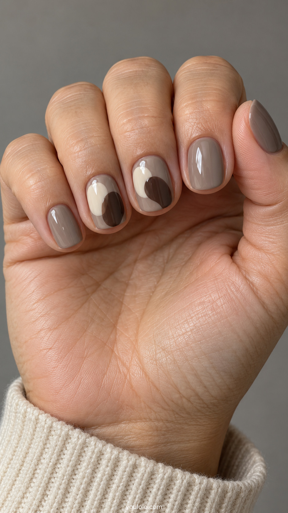 Short squoval nails: greige nails with two overlapping irregular cream and espresso pebble blobs on ring and middle, rounded organic shapes.