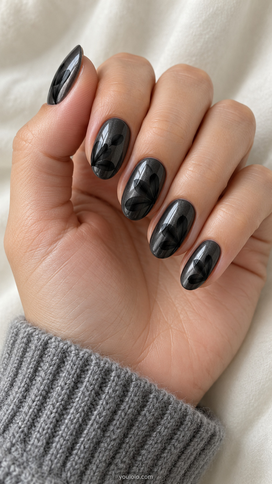 Dark gunmetal oval nails with overlapping translucent black petal silhouettes along one side