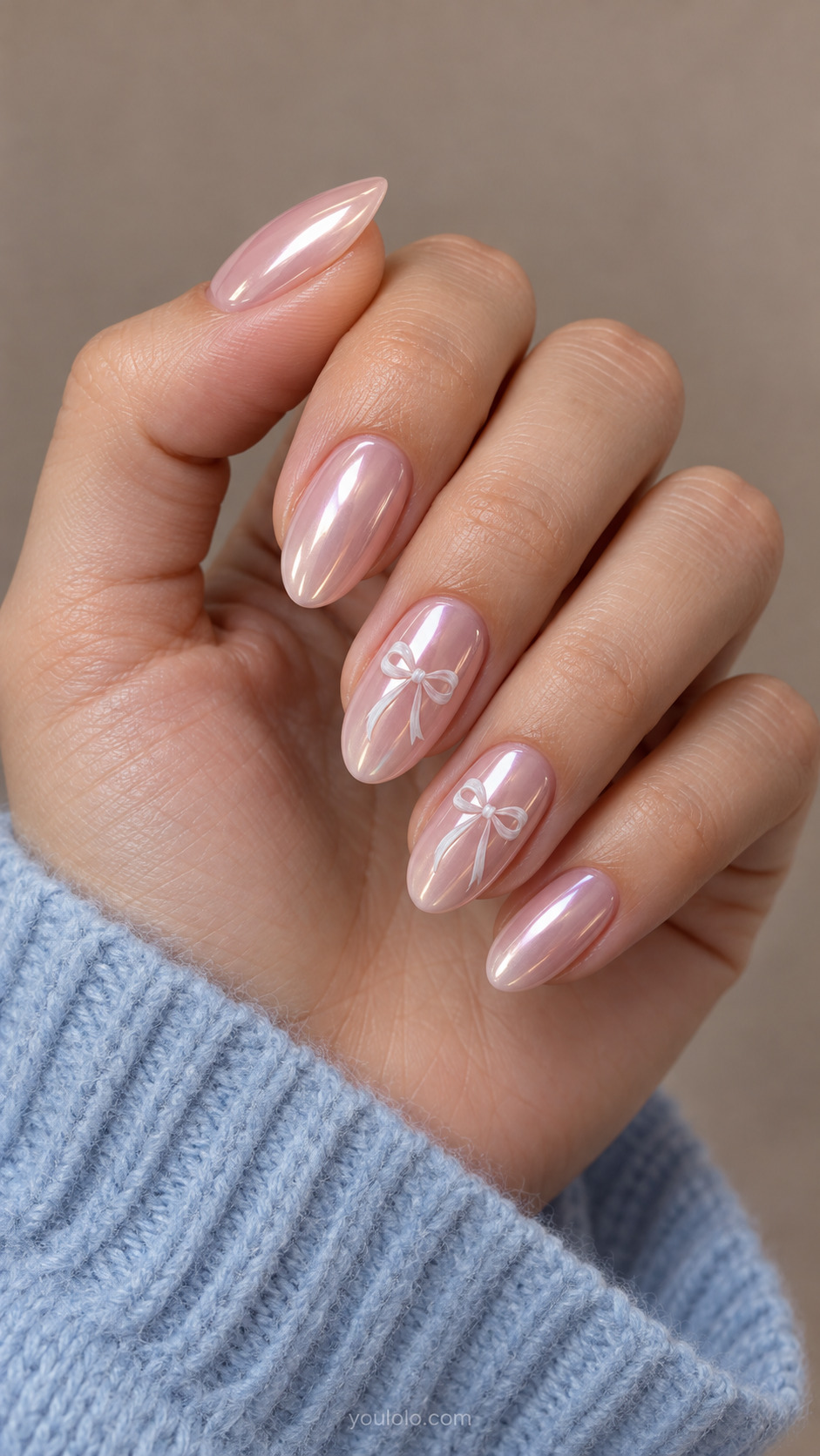 Blush pearl chrome almonds with tiny white ribbon bows on two accent nails.