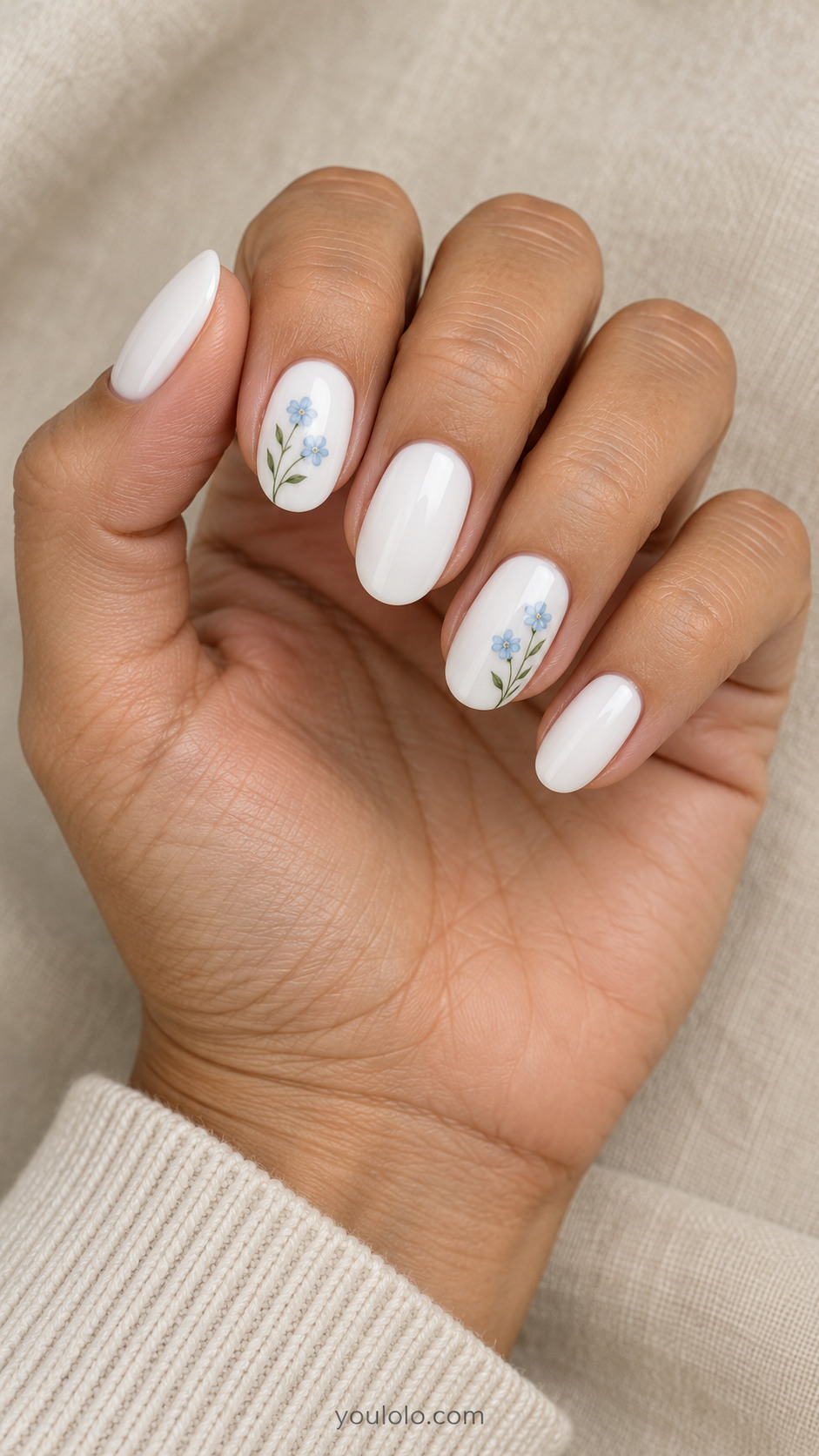 White oval nails with tiny blue flowers and green stems on two nails