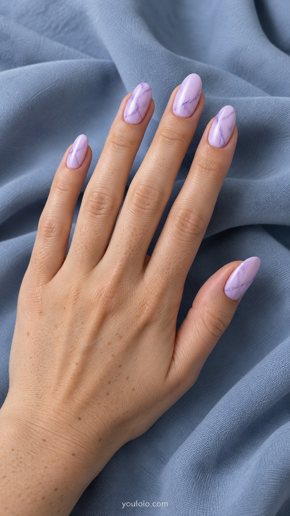 Medium oval acrylic extensions opaque pale lilac with sparse deeper lavender irregular fine marble veins
