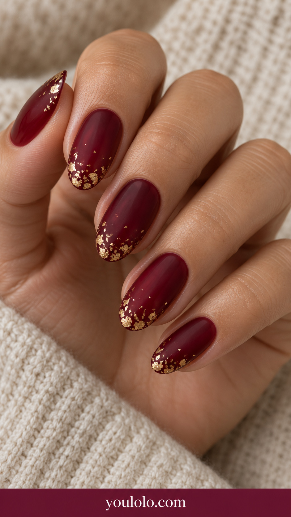 medium oval sheer cherry red nails tiny flat muted gold foil flecks only near tips fading sparsely into center on a naturally relaxed adult hand