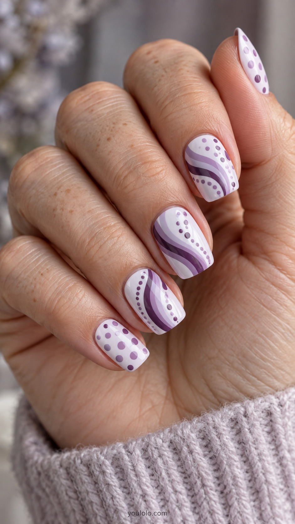 Lilac nails with curved purple brushstrokes and matching dotted accents.