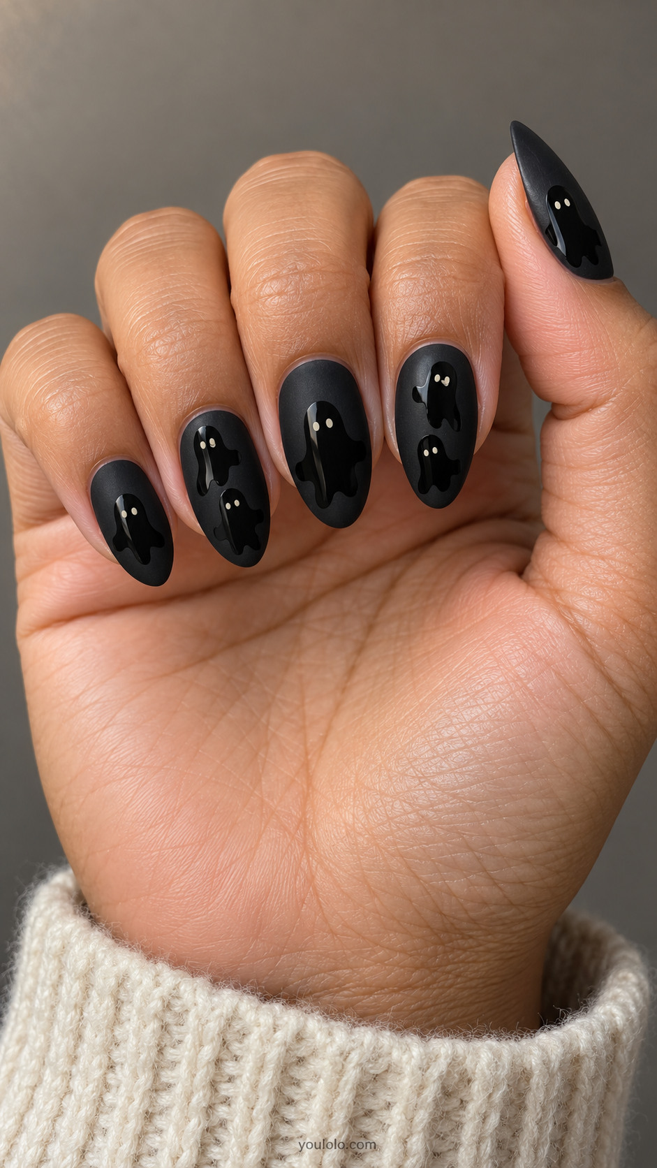 Matte black almond nails with tonal glossy black ghost silhouettes and tiny ivory eyes