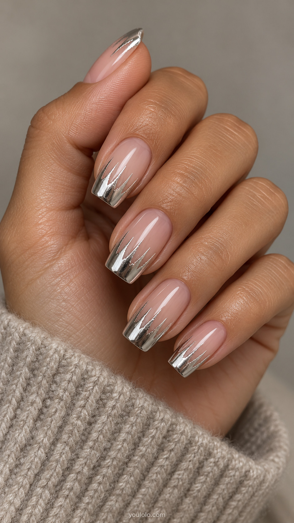 Nude tapered square nails with silver chrome tips and fine uneven icicle points.