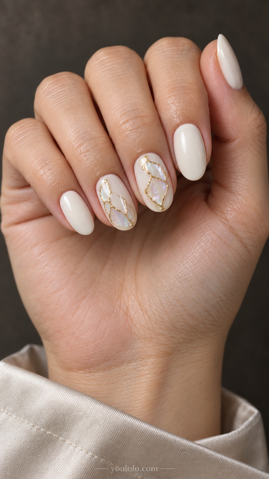 Medium oval ivory nails with small pearly inlay fragments edged in gold on two accents