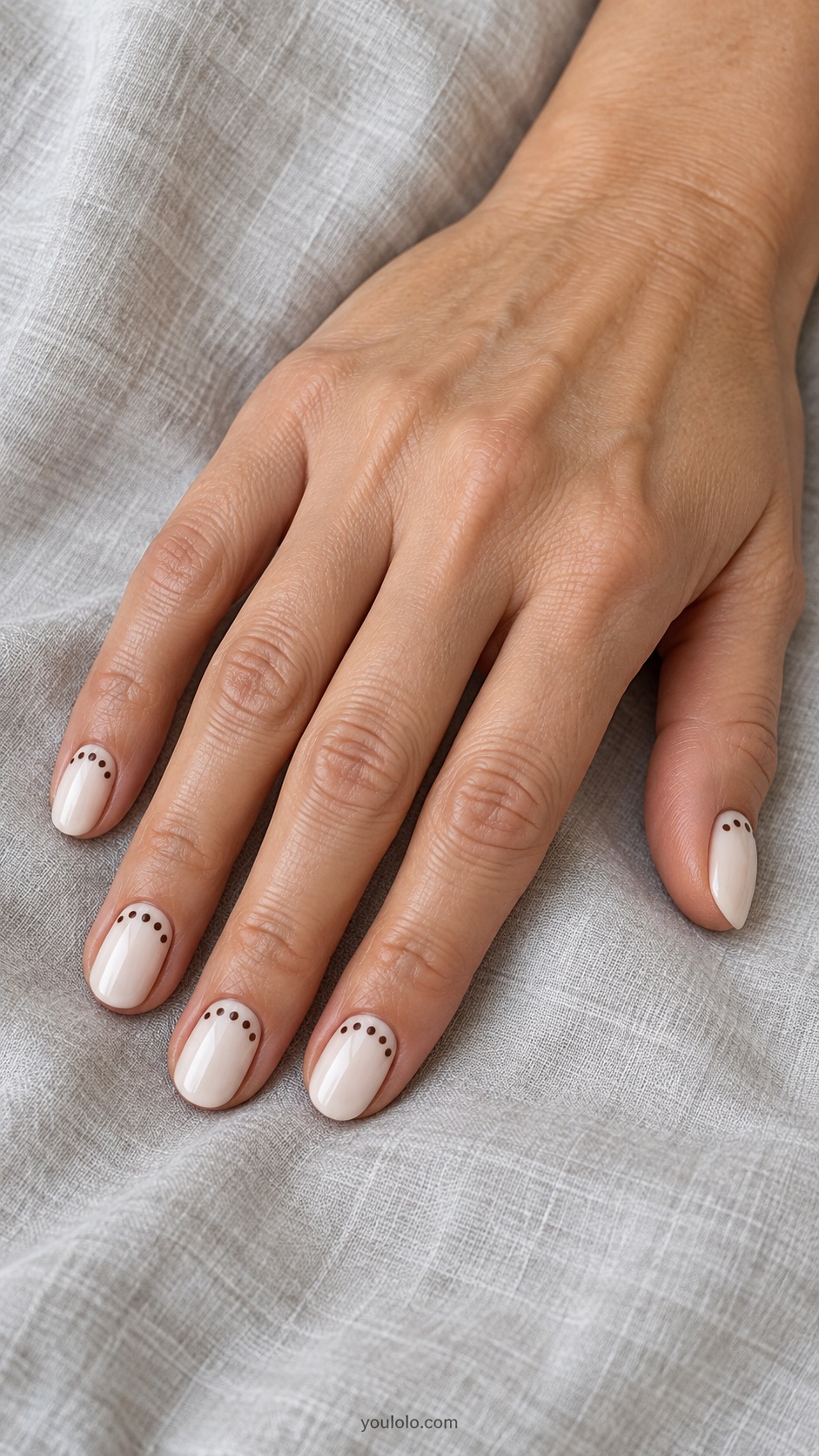 Brown Dot Half Moons — short oval ivory base chocolate dots arranged around cuticle half moon shape center left plain