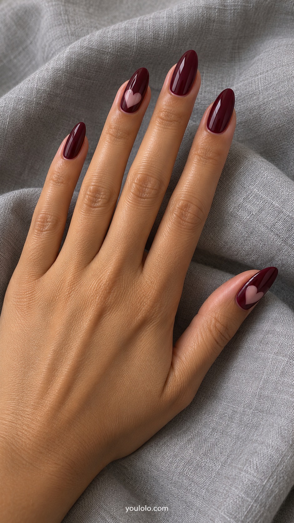 Medium almond acrylic extensions glossy burgundy with small pale pink heart negative spaces on ring and thumb