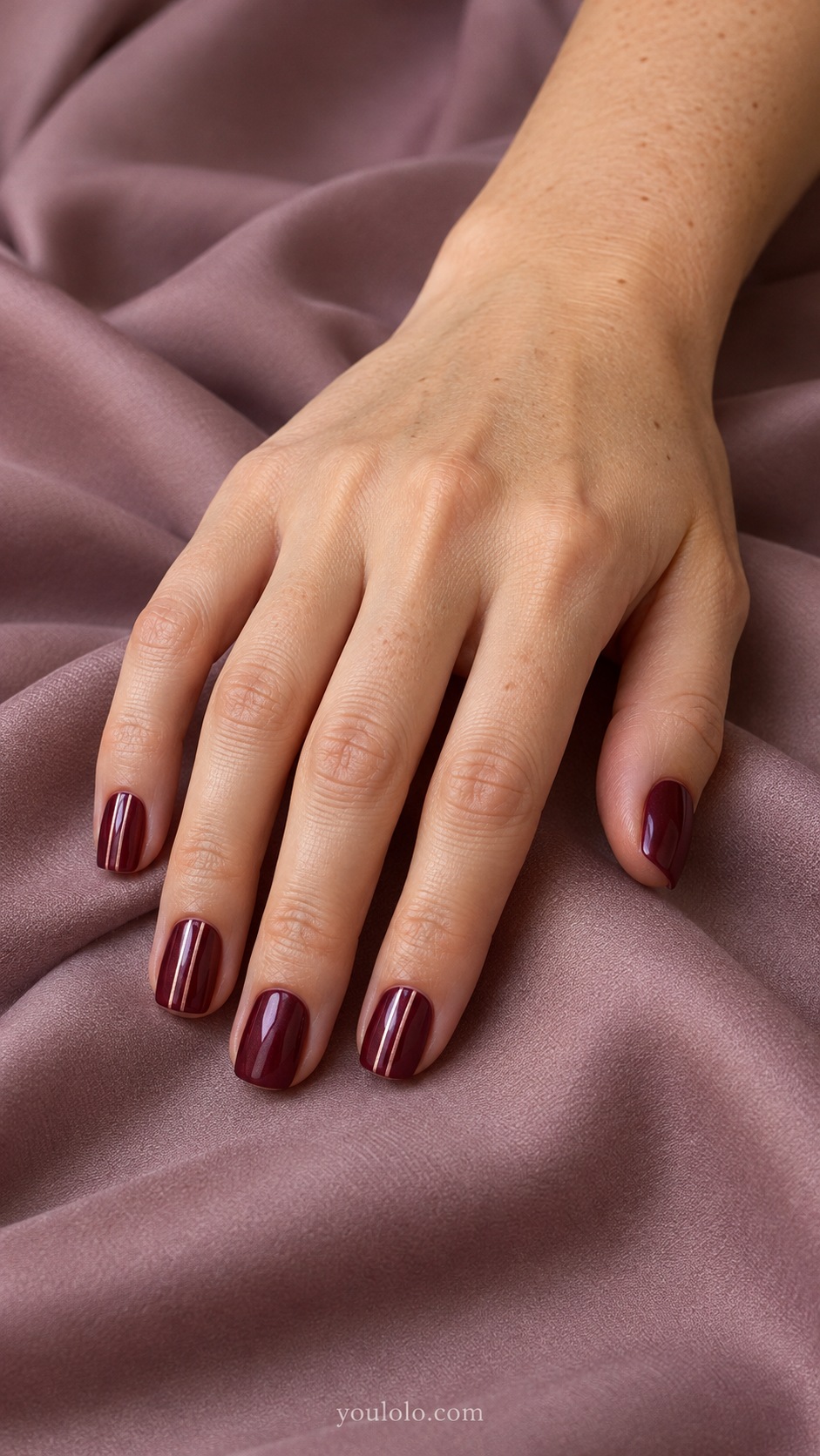 Short square burgundy pearl nails selected accent nails with fine parallel pale rose vertical pinstripes, other nails plain