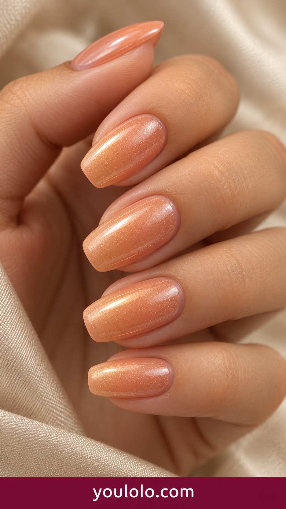 Medium squoval apricot nude nails with subtle warm pearl chrome sheen on a naturally curled young adult hand