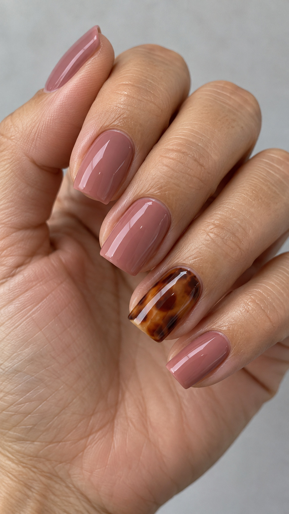 Pink with a Tortoiseshell Accent: Dusty rose square nails with an amber-brown tortoiseshell ring nail on a naturally posed adult hand