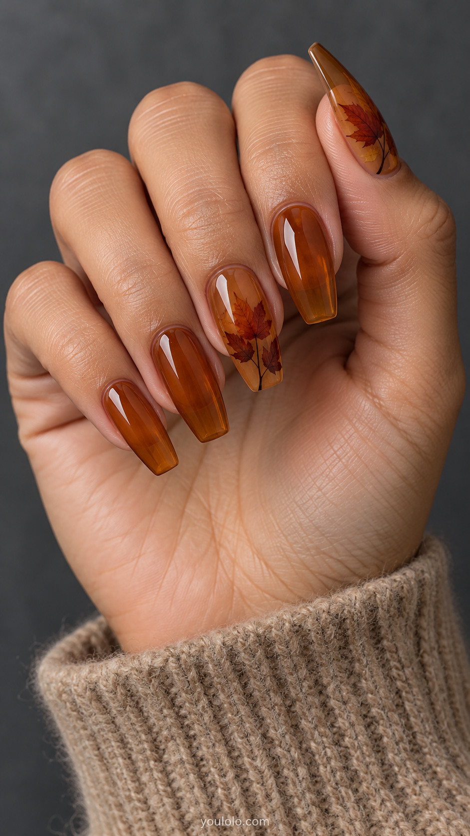 Amber jelly coffin nails with russet maple leaf artwork on the thumb and middle finger.
