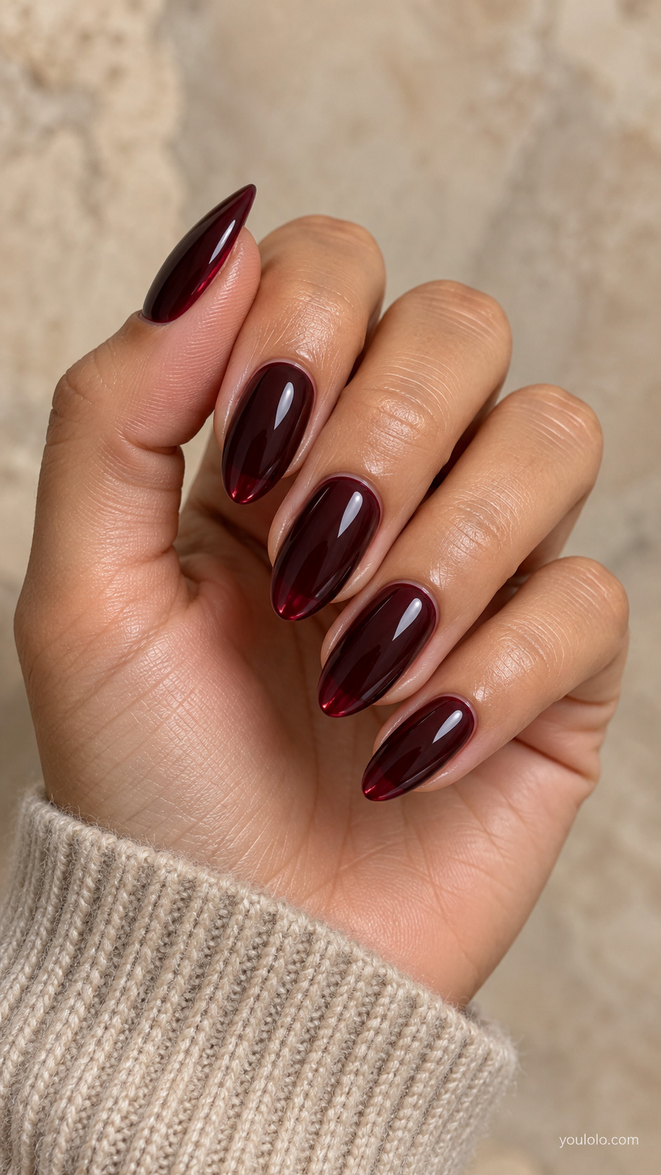 Elongated almond nails in glossy black cherry burgundy with red depth near the edges.