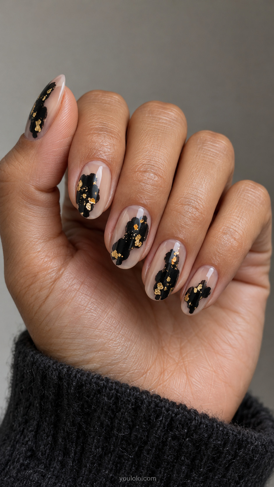 Nude oval nails with black inkblot shapes containing gold leaf